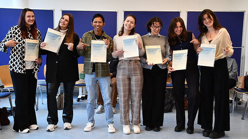 Gruppenbild: Die Stipendiatinnen stehen nebeneinander, lachen und halten ihre Urkunden in den Händen.  