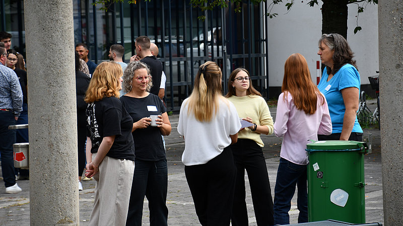 Gruppe von Studierenden und Anleiter*innen im Gespräch vor der Hochschule