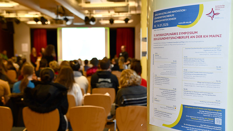 Blick in die Aula beim Interdisziplinären Forschungssymposium des Fachbereichs Gesundheit und Pflege. Im Vordergrund ist das Programm der Veranstaltung zu sehen. 